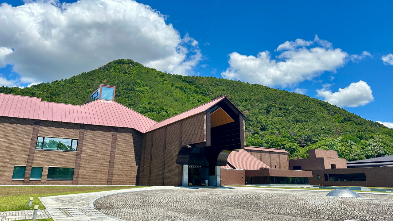 福島県立美術館外観。広大な敷地の中にレンガ造りの建物や庭園があり、背景には福島のシンボル信夫山も広がります