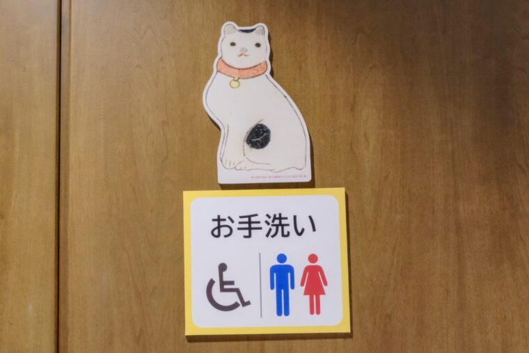 「お手洗い」の表示の上に猫がいる